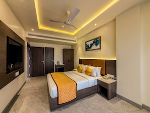 A modern hotel room with a bed, bedside table, nightstand, ceiling fan, artwork, and a television mounted on the wall. - ZiP By Spree Hotels Pandharpur (Pandharpur)