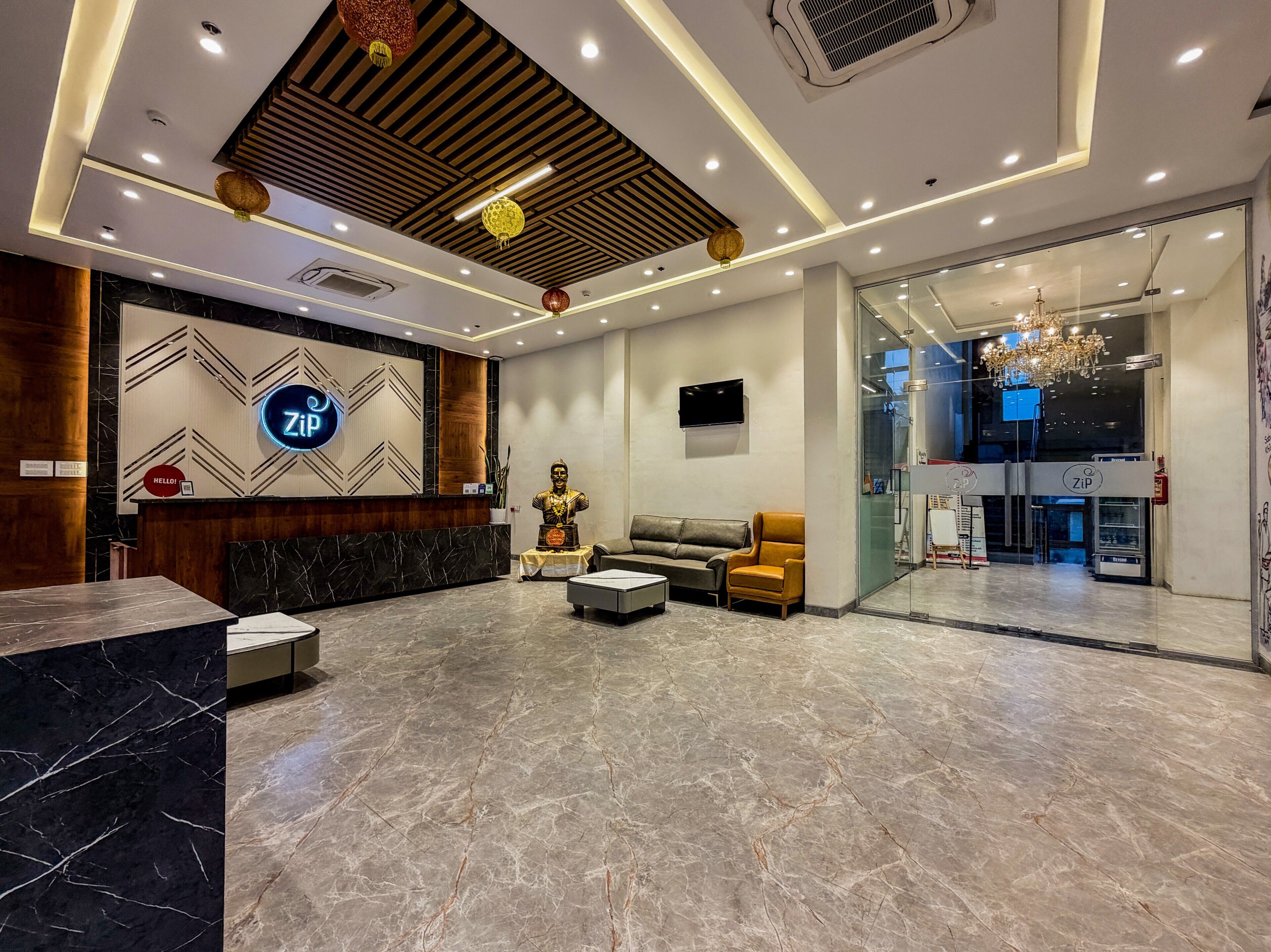 A hotel lobby with a reception desk, seating area, and a statue.
