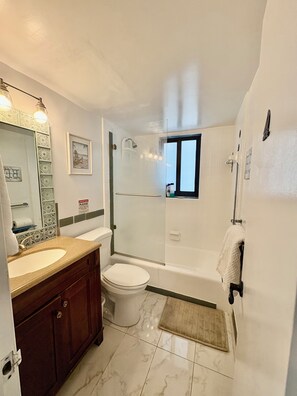 Ein Badezimmer mit Waschbecken, Toilette, Dusche und einem Fenster.