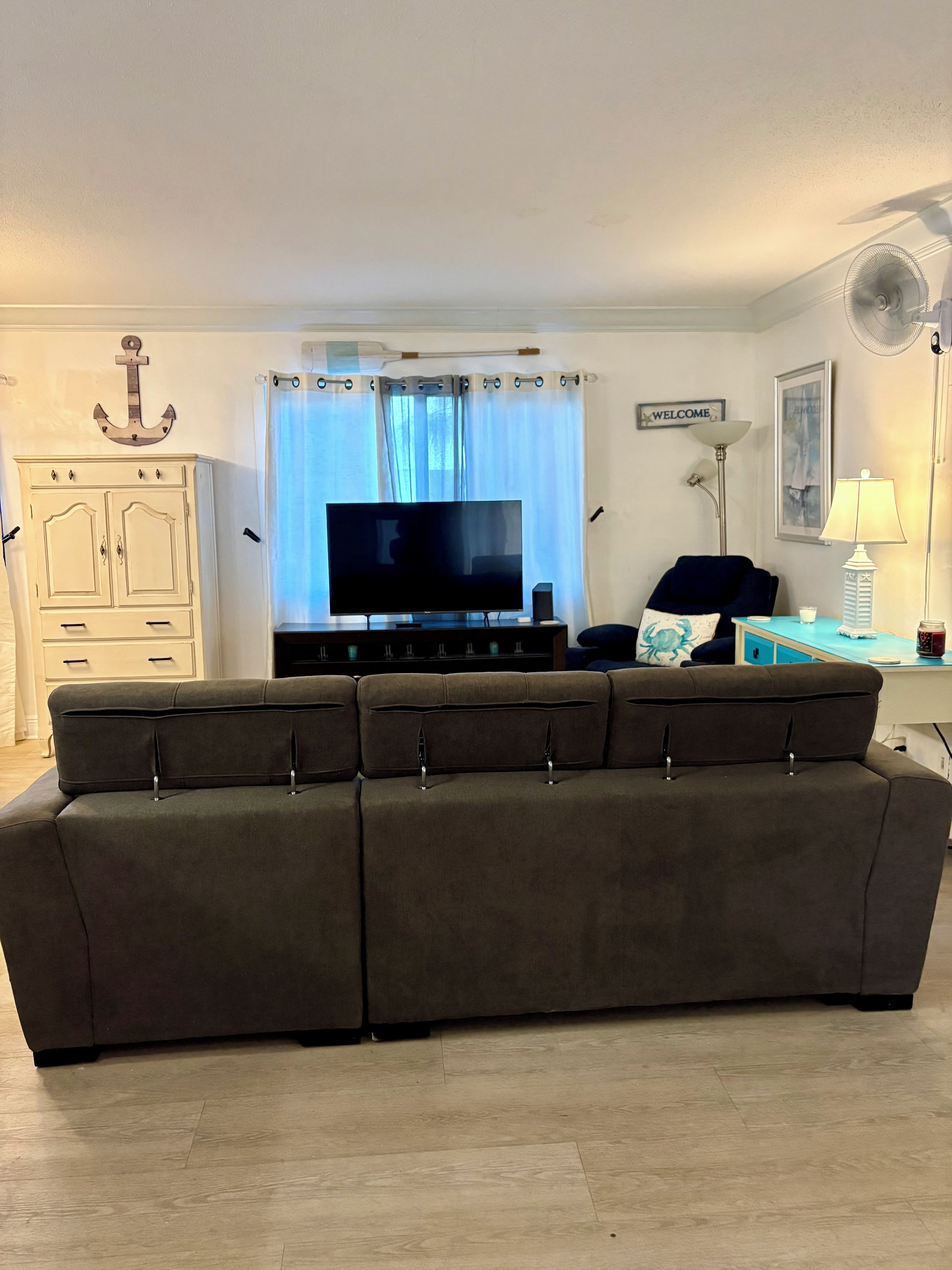 Un salon comprenant un canapé, un téléviseur, un meuble, une lampe et un ventilateur.