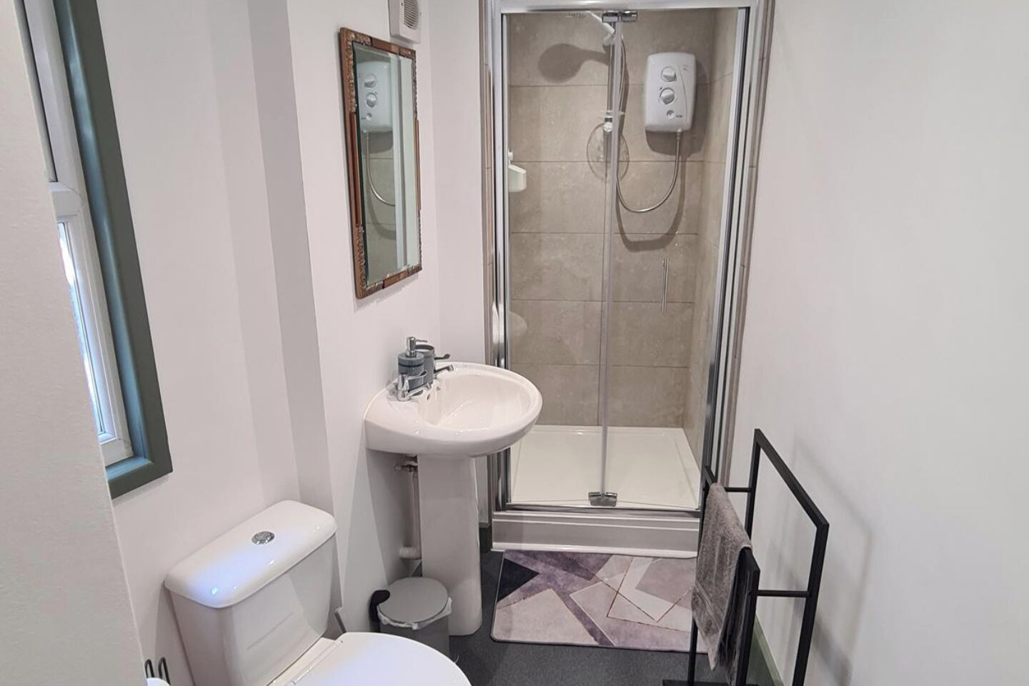 A bathroom with a toilet, sink, and shower.