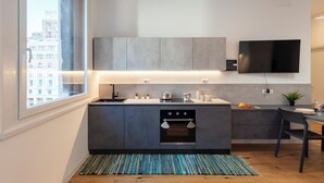 Cocina moderna con un amplio ventanal, horno empotrado y televisor de pantalla plana en la pared.