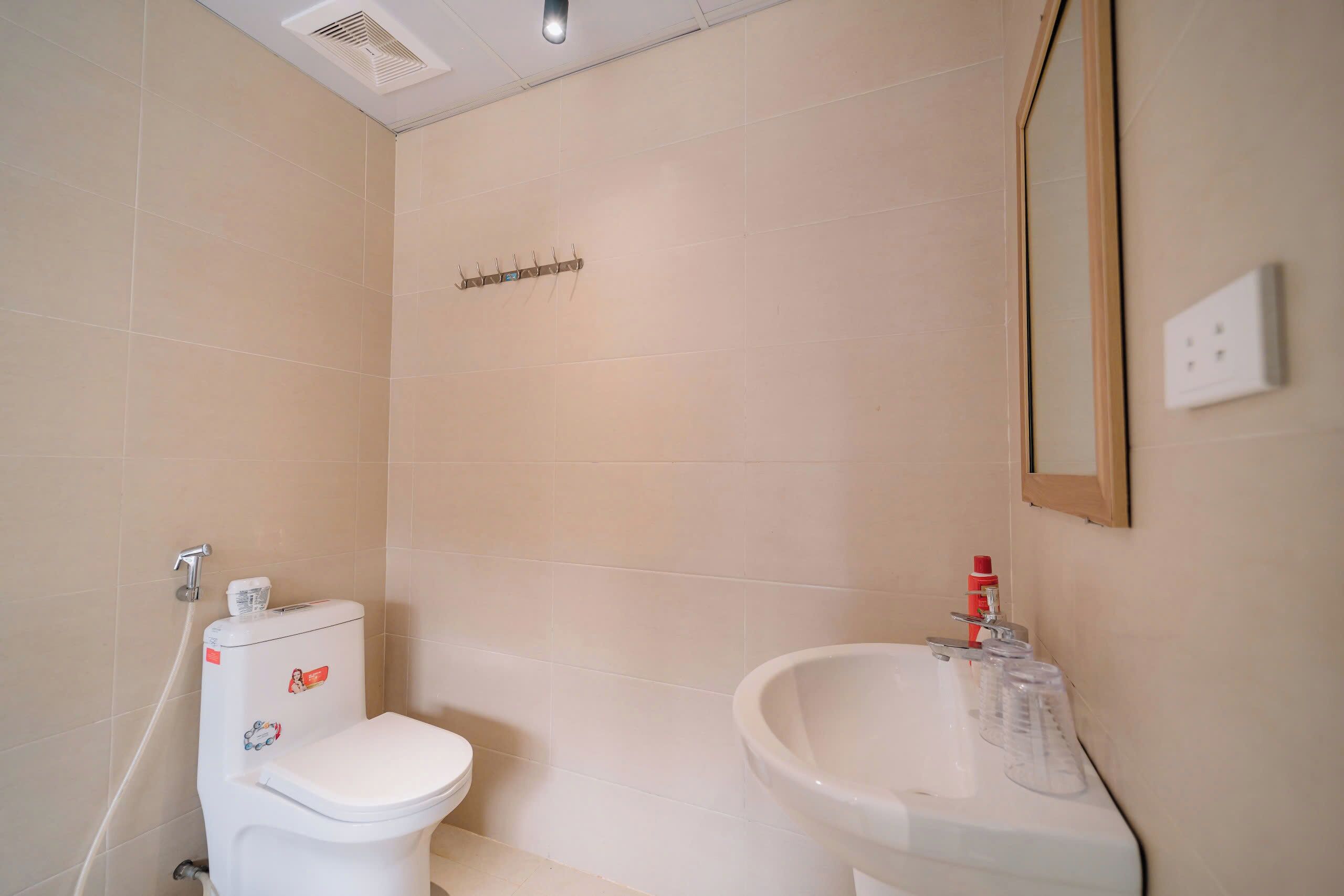 A bathroom with a toilet, sink, and mirror.