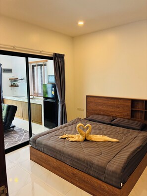 Habitación de hotel moderna con una cama grande, cabecera de madera y puerta corredera de vidrio que da a un balcón.