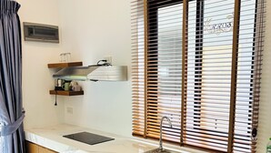 Una cocina moderna con armarios de madera, encimera de mármol, pileta de acero inoxidable y ventana con persianas.