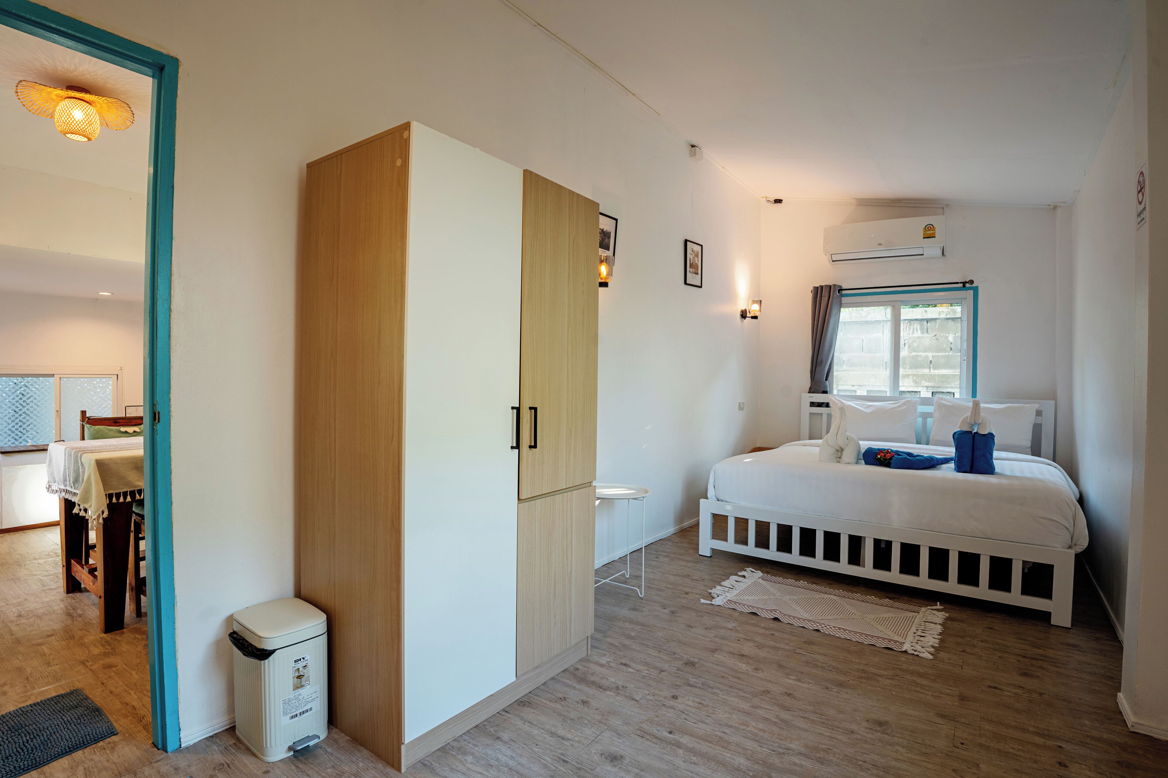 Un dormitorio con cama, armario, mesita de noche y ventana con cortinas.