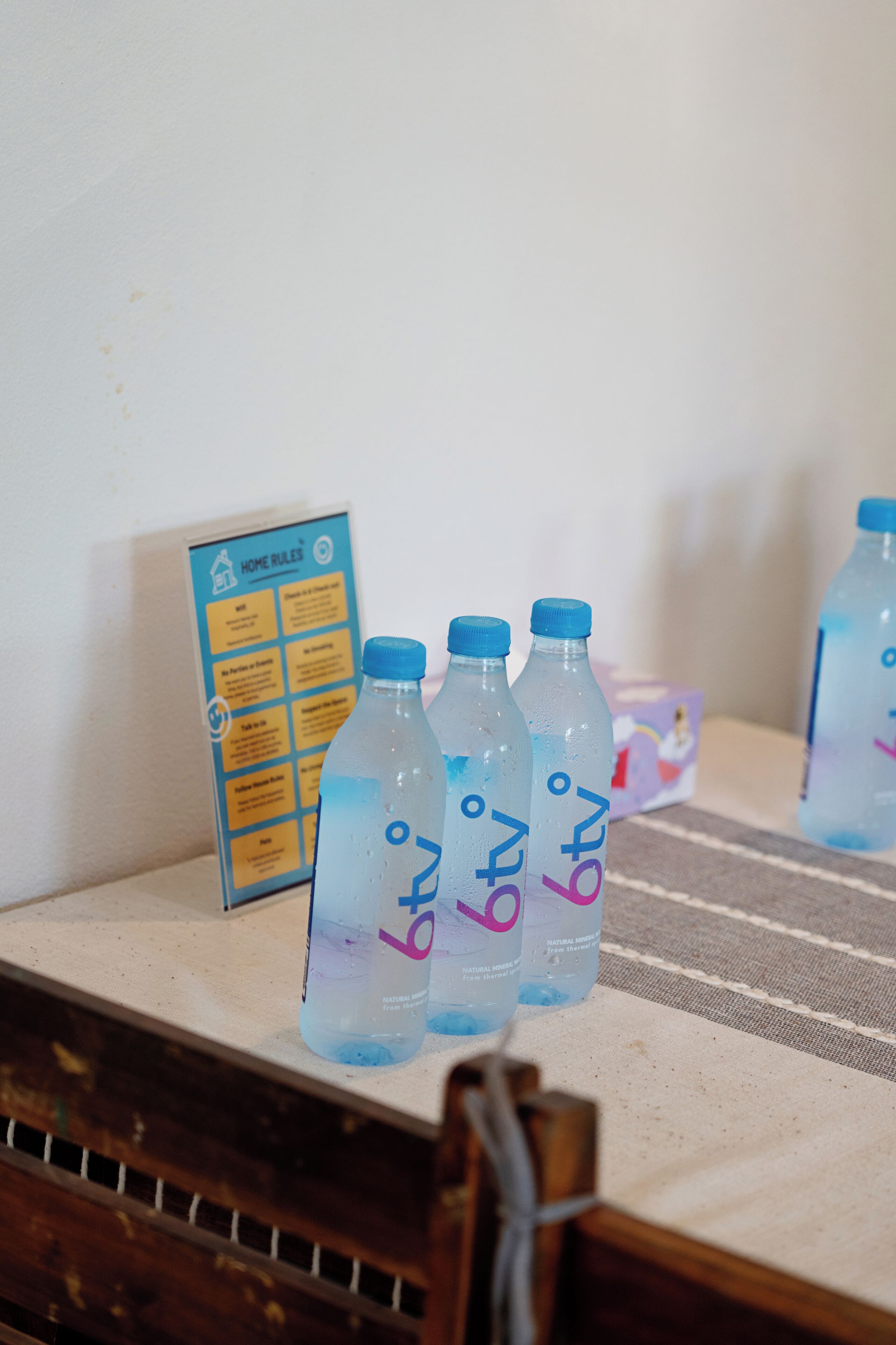 Una mesa con botellas de agua y un cartel con normas de la casa.
