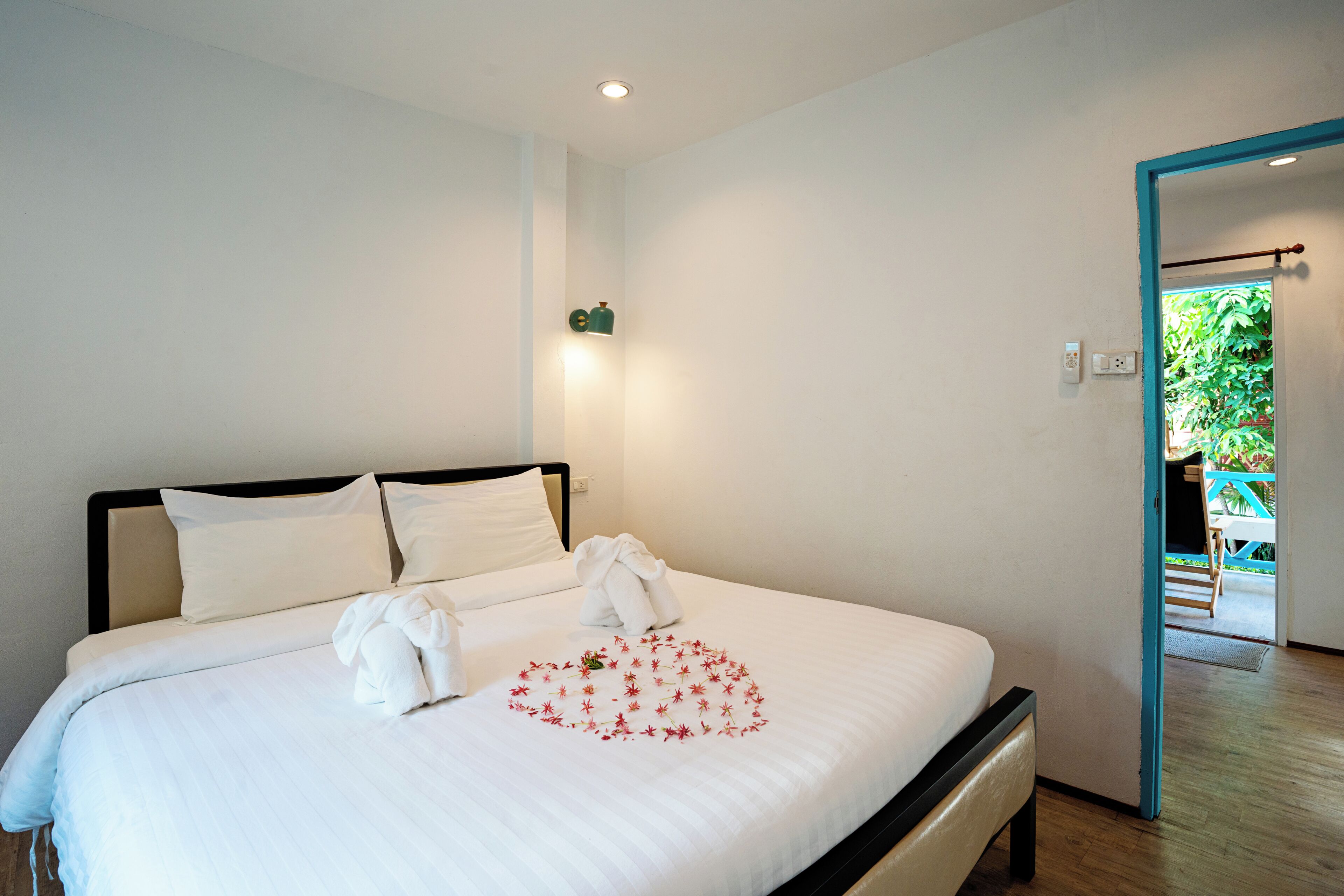 Een net opgemaakt bed met witte lakens en een bloemstuk in de vorm van een hart op het beddegoed.