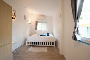 A bedroom with a bed, bedside table, wall-mounted light, air conditioning unit, and a window with curtains. - Dream Villa Beachfront Sunset (Koh Samui)