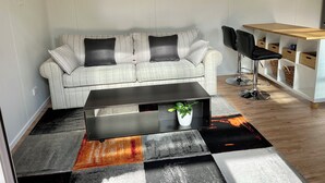 Ein Wohnzimmer mit einer Couch, einem Couchtisch und einer Bar mit Stühlen und Stauraum.