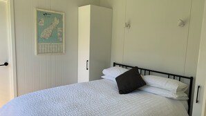 Ein Schlafzimmer mit Bett, weißen Wänden, einer Karte und einem Kleiderschrank.