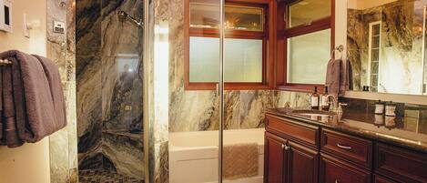 A bathroom with a glass-enclosed shower, a bathtub, and a vanity with a mirror.