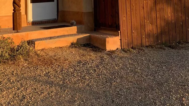Un bâtiment recouvert d’enduit, avec une porte en bois, une antenne parabolique et une petite fenêtre.