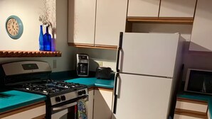 Une cuisine compacte équipée d’une cuisinière à gaz, d’un four, d’un four à micro-ondes et d’un réfrigérateur.