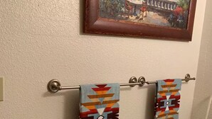 Une salle de bain avec un porte-serviettes sur lequel sont pliés deux serviettes aux motifs géométriques.
