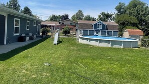 Un patio trasero con piscina, tobogán y área de patio cercada.