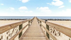 A wooden pier leading to a beach with a clear sky. - Salt Air Nook - Pool Access (Jekyll Island)