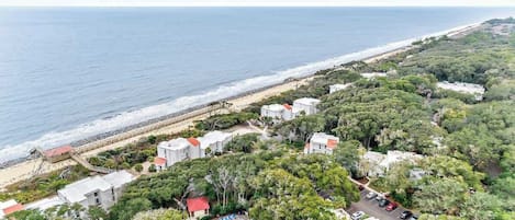 A coastal property with a swimming pool, beach access, and dense greenery.