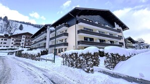 Un hôtel à plusieurs étages doté de balcons, entouré d’un paysage enneigé et d’arbres.