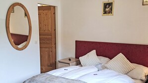 Une chambre à coucher avec un lit, une table de chevet, un miroir, une porte en bois et un tableau encadré accroché au mur.