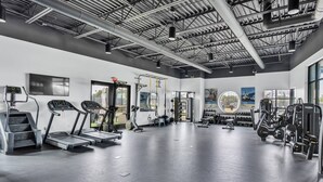 A gym with treadmills, weight machines, and a large mirror. - King Suite & Twin Room | Condo at The Well Mouratoglou | Tennis & Pickleball (Zephyrhills)