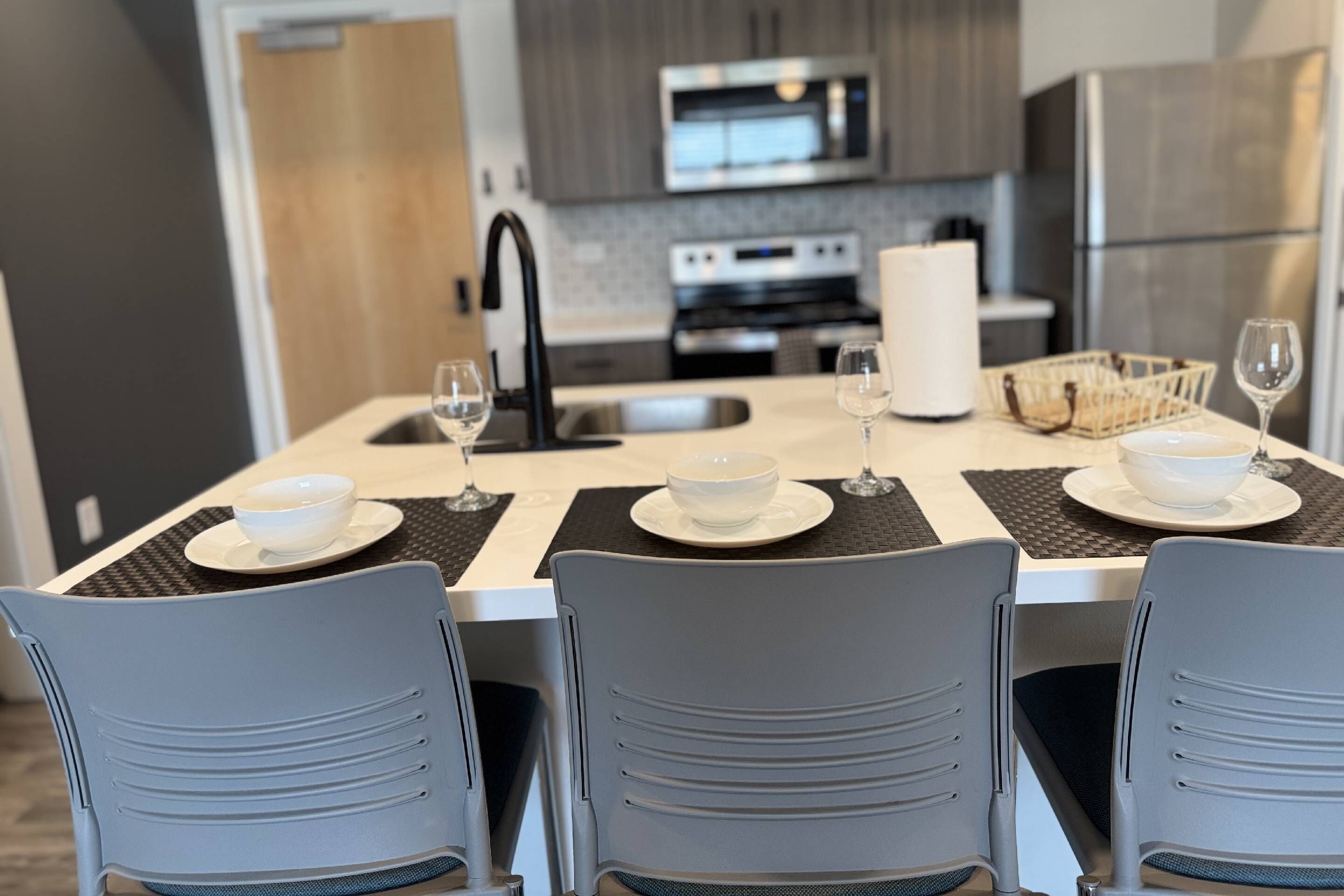 Une cuisine moderne avec une table à manger pour quatre personnes, comprenant un îlot central avec un saladier et des verres à vin.