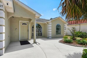 A residential building with a beige facade, a front door, and arched windows. - Private home near the beach, with yard, private pool, game room, and $300 of Free Activities Daily! (Panama City Beach)