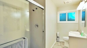 Une salle de bain avec douche, toilettes et lavabo.