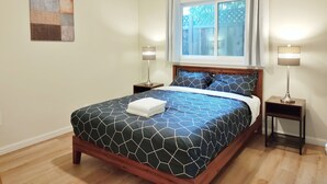 A bedroom with a bed, two bedside tables, a window with curtains, and a wall art piece. - 261-6 Cozy 2-Bedroom Apartment near Downtown Mountain View (Mountain View)