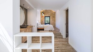 Ein modernes Schlafzimmer mit Steinwand, einem großen Bett, einem Nachttisch und einem weißen Konsolentisch im Vordergrund.