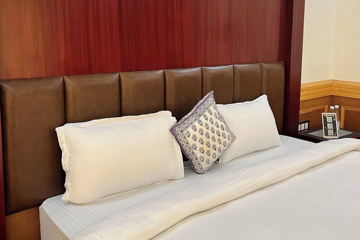 A neatly made bed with a wooden headboard, two pillows, and a decorative pillow.