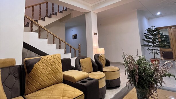 A modern living room with a staircase, comfortable seating, and a potted plant. - LADAKH COUNTRY INN (Leh)