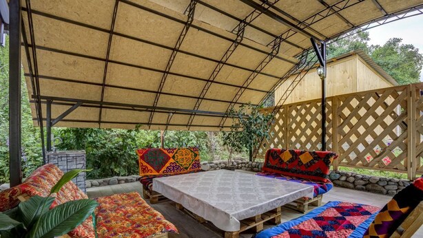 Une terrasse extérieure avec des meubles en bois, une table et un espace abrité.