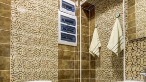 Une salle de bain avec des murs recouverts de mosaïques, des toilettes, un lavabo et un espace douche.