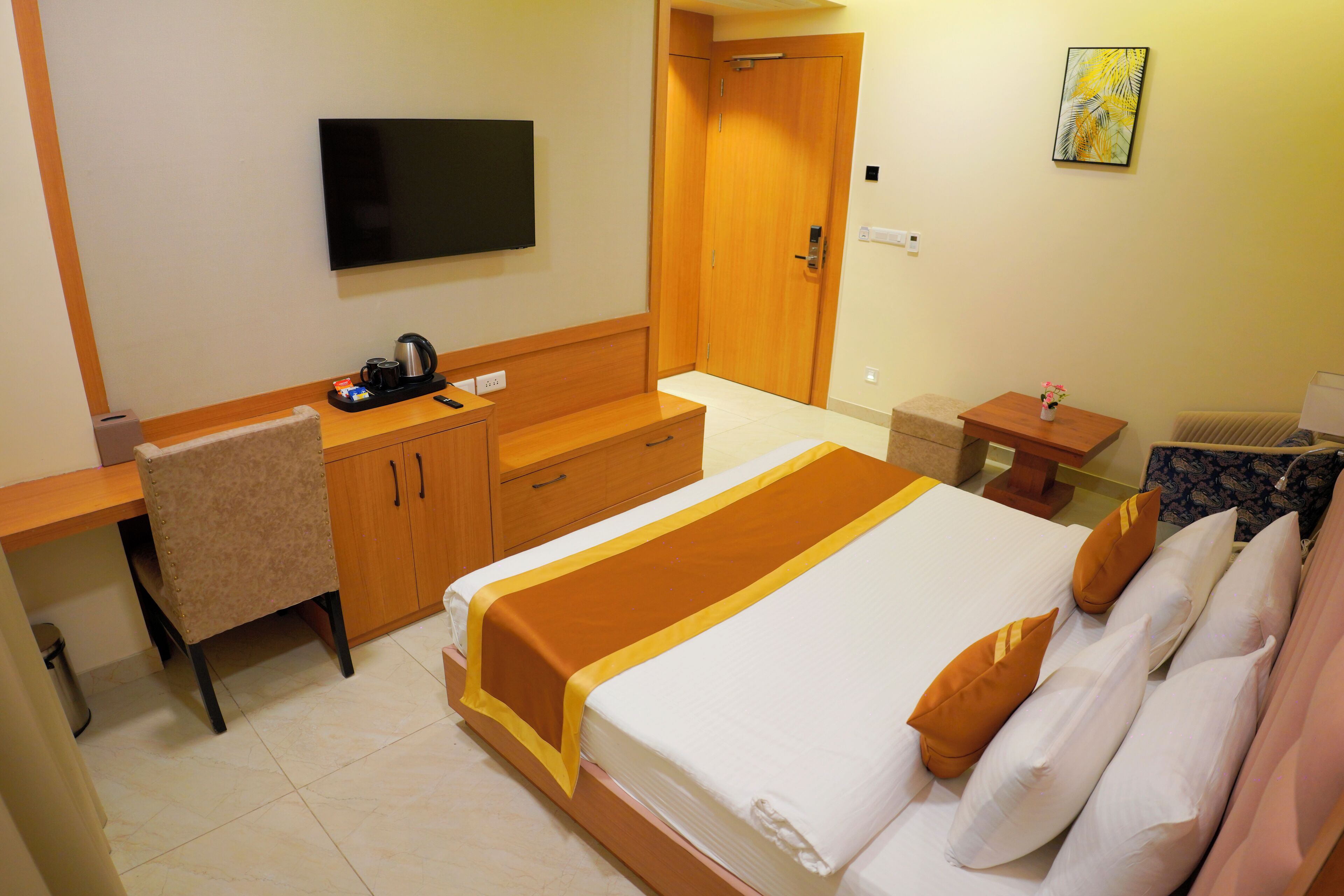 Una habitación de hotel con una cama, un escritorio, una silla, un televisor y una puerta.