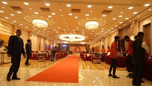 A spacious hotel lobby with a red carpet, multiple tables, and a chandelier. - Hotel Cheer Royale (Bareilly)