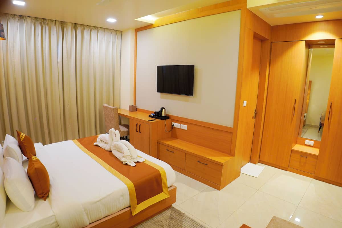 Quarto de hotel com cama, televisão, guarda-roupa e espelho.