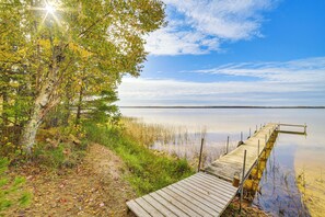 A wooden dock extending into calm water, surrounded by trees and vegetation. - Dock & Fire Pit: Lakefront Cottage in Gould City! (Gould City)