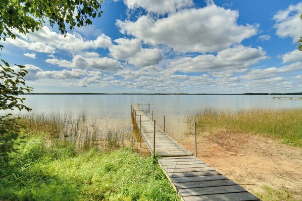 Een houten steiger die uitloopt in een rustig meer, met een heldere lucht erboven.