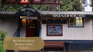 Un edificio rústico con un letrero que dice "RIO NIDO Roadhouse" y una pizarra que anuncia eventos.