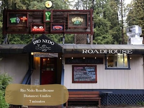 Un edificio rústico con un letrero que dice "RIO NIDO Roadhouse" y una pizarra que anuncia eventos.
