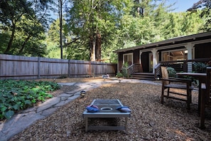 A backyard with a wooden deck, a barbecue area, and a stone pathway. - Hot Tub Retreat Near Russian River • BBQ • Family Friendly (Guerneville)