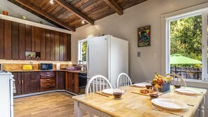 Een keuken met houten kastjes, een witte koelkast en een eettafel voor vier personen.