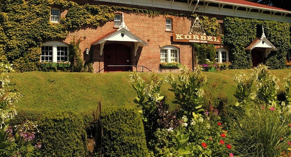 Un edificio de ladrillo con un letrero que dice "KORBEL" y un jardín al frente.