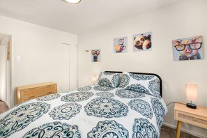A bedroom with a bed, a bedside table, a lamp, and wall art. - Hot Tub Retreat Near Russian River • BBQ • Family Friendly (Guerneville)