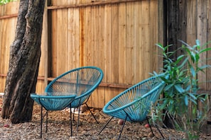 Two blue chairs with metal legs, positioned on a leaf-covered ground against a wooden fence. - Hot Tub Retreat Near Russian River • BBQ • Family Friendly (Guerneville)