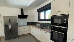 A modern kitchen with stainless steel appliances, white cabinetry, and a window providing natural light.