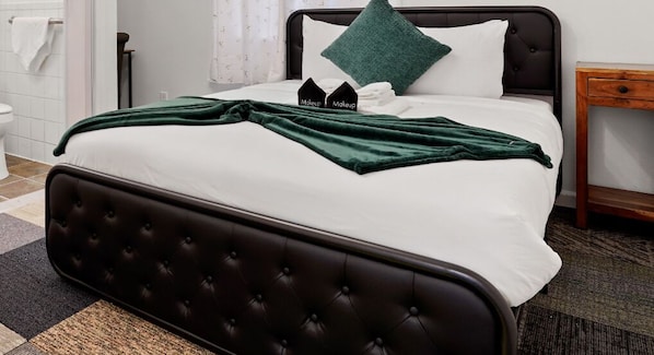 A neatly made bed with a dark headboard, white bedding, and a green throw blanket. - Peaceful 1BR Stay - Golf & Beach (Pacifica)