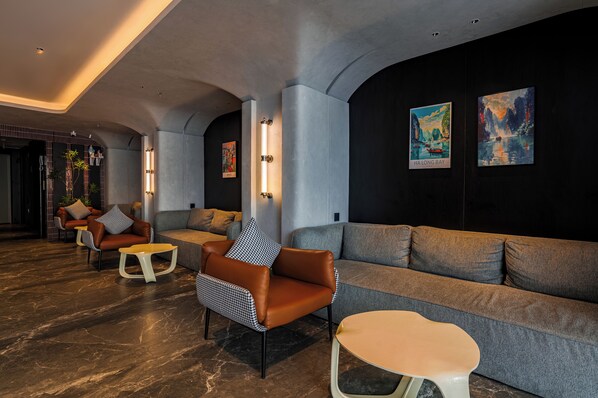 Un espace de détente moderne, aménagé avec différents types de sièges, notamment des canapés et des fauteuils, et agrémenté d’œuvres d’art aux murs.