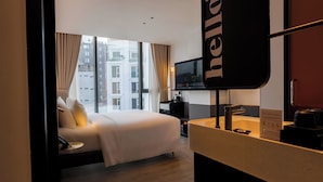 A hotel room with a bed, a bedside table, a TV, and a view of the city. - The Signature Hotel Saigon (Ho Chi Minh City)